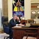 Bush at work in the Oval Office, with a poster of his favorite movie nearby.